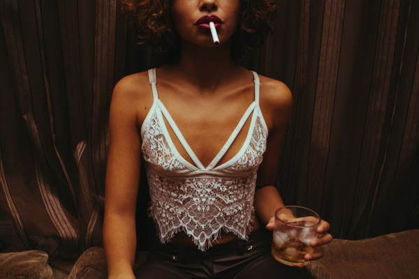 Close-up Photo of Woman Holding Drink in Hand With Cigarette on Her Lips